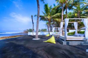a beach with a white swing and palm trees at Dewangga 5 BR beachfront Villa JU25 in Blahbatu
