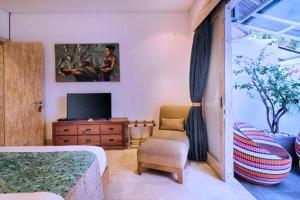 a bedroom with a bed and a tv and a chair at Dewangga 5 BR beachfront Villa JU25 in Blahbatu