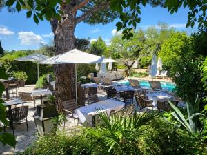 an outdoor patio with tables and chairs and a pool at Hotel Bastide & SPA - Villa de Lourmarin in Lourmarin