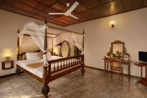 Schlafzimmer mit einem Himmelbett und einem Deckenventilator in der Unterkunft River Loft Nature Resort in Pathegama
