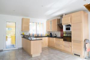 a large kitchen with wooden cabinets and appliances at EXIGEHOME - Maison à 2 pas de la foret - 10 min de Versailles in Vélizy-Villacoublay +12 photos