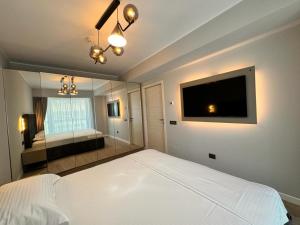 1 dormitorio con 1 cama blanca y TV de pantalla plana en Zora Bliss, en Năvodari