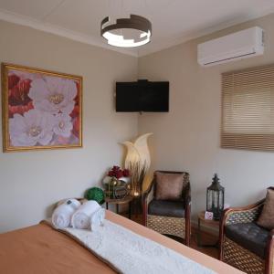 a bedroom with a bed and two chairs and a tv at De Witte Huis in Bethlehem