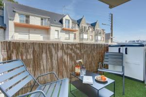Un patio con una silla y un refrigerador y una mesa. en L'Emérillon - Appt à 200m de la plage, en Saint-Cast-le-Guildo