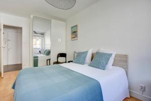 Un dormitorio con una gran cama blanca con almohadas azules. en L'Emérillon - Appt à 200m de la plage, en Saint-Cast-le-Guildo
