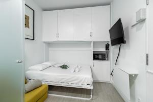 a small white room with a bed and a tv at Sol Apartment III - En el centro de Madrid in Madrid