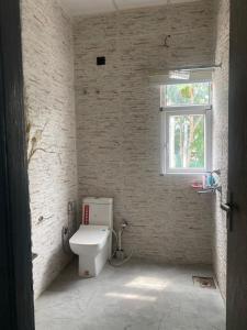 a white bathroom with a toilet and a window at X-Plosiv Farm in Noida +38 photos