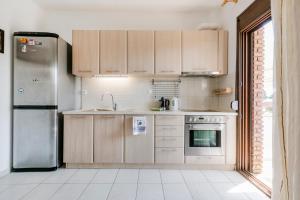 a kitchen with wooden cabinets and a stainless steel refrigerator at Delmare Delia maisonette in Yerakiní