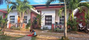 a man kneeling on the ground in front of a house at Jean apartments in Panglao