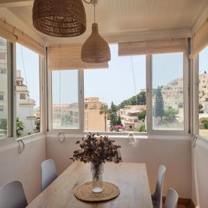 a dining room with windows and a table with flowers at Portichuelo Playa in Almuñécar