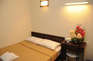 ein kleines Zimmer mit einem Bett und einem Tisch mit Blumen in der Unterkunft Desaru Penawar Inn in Desaru