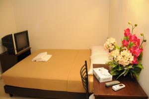 ein Hotelzimmer mit einem Bett und einem Tisch mit Blumen in der Unterkunft Desaru Penawar Inn in Desaru