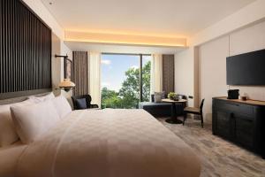 ein Hotelzimmer mit einem großen Bett und einem großen Fenster in der Unterkunft Padma Hotel Semarang in Semarang