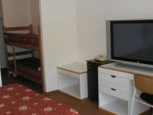 um quarto com uma televisão e uma secretária com um computador portátil em Hotel Restaurant Le Pavillon Carina em Gap