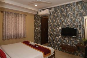 a bedroom with a bed and a tv on a wall at virat inn in Bangalore