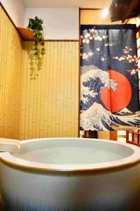 a bath tub in a room with a painting of the tsunami at Karin House in Takayama +81 photos