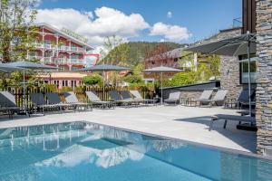 una piscina in un hotel con sedie e ombrelloni di Summit Seefeld a Seefeld in Tirol