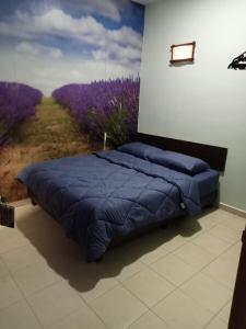 ein Schlafzimmer mit einem blauen Bett und einem Gemälde an der Wand in der Unterkunft Desaru Penawar Inn in Desaru
