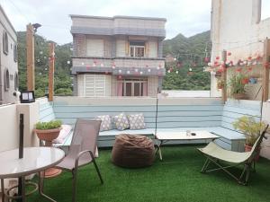 un patio en la azotea con sofá, mesas y sillas en 七十腳落背包客棧, en Isla Verde