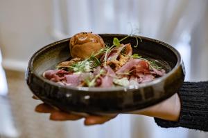 a person holding a bowl of food in their hand at Prawdzic Family Resort & Wellness in Gdańsk