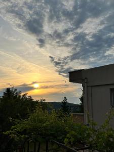 un cielo nuvoloso con il sole che tramonta dietro un edificio di Guesthouse P&A a Budua