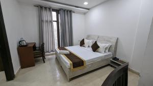 a bedroom with a bed and a desk and a window at Hotel Prime Royalty Malviya Nagar in New Delhi