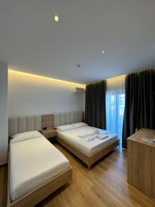 sypialnia z 2 łóżkami i oknem w obiekcie GL Hotel Ksamil w mieście Ksamil