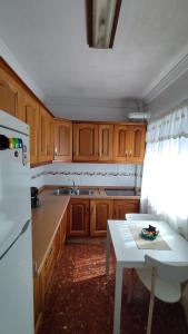 eine Küche mit Holzschränken und einem weißen Tisch in der Unterkunft Apartamento Peñuelas Torrox in Torrox + 17 Fotos