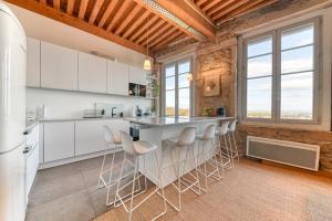 Una cocina con gabinetes blancos y taburetes de bar. en GuestReady - Canut Typique avec vue sur Lyon, en Fourvière