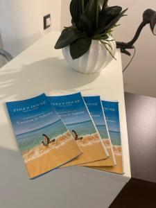 a table with three brochures on a table with a vase at Tina's House Luxury Room in Copertino +5 photos