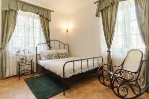 a bedroom with a bed and a chair and windows at Apartamenty w Dworku Cheval in Kraków