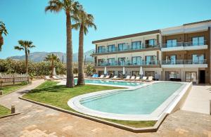 duży budynek z basenem i palmami w obiekcie Malia Bay Beach Hotel & Bungalows w mieście Malia