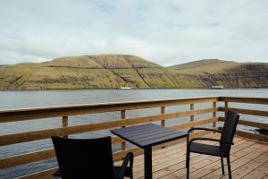 a table and chairs sitting on a deck overlooking a body of water at Seadreams Nest - Luxurious Waterfront Retreat in Vestmanna