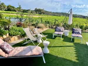 een groep ligstoelen en een parasol op het gras bij jolie maison neuve au coeur des vignes in Cogolin