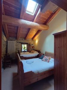 two beds in a room with wooden ceilings at Albergo diffuso La Marmu Osteria della Croce Bianca in Marmora