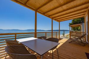 una mesa y sillas en una terraza con vistas al océano en Glamping & Holiday Home experience - Camp Dole, en Živogošće