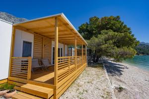 een huis op het strand met een terras bij Glamping & Holiday Home experience - Camp Dole in Živogošće