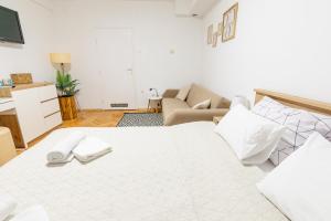 a bedroom with a large white bed and a couch at Apartman Lumi in Čakovec