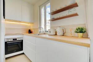 a white kitchen with white cabinets and a sink at Cosy Duplex in Boulogne-Billancourt