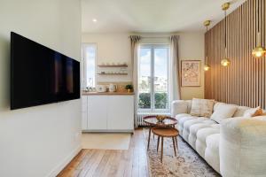 a living room with a couch and a flat screen tv at Cosy Duplex in Boulogne-Billancourt