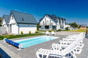 een huis met een zwembad en ligstoelen bij Cichy Domek - Podgrzewany Basen, Parking, Aneks Kuchenny in Karwia