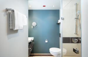 a bathroom with a toilet and a shower at Leonardo Royal Hotel Munich in Munich