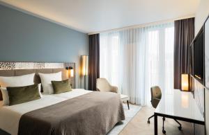 Cette chambre comprend un lit et un bureau. dans l'établissement Leonardo Royal Hotel Munich, à Munich