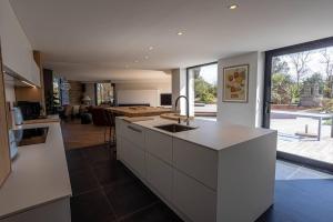 a kitchen with white cabinets and a large window at les ajoncs d or, Ploumanach Exceptionnelle in Perros-Guirec