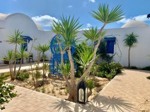 un cortile con palme e un edificio blu e bianco di Tamalou Djerba a Midoun