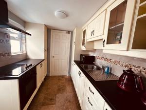 a kitchen with white cabinets and a black counter top at Coastal Charm in Donegal