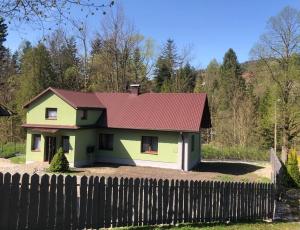 ZłatnaDomek w górach pod Rysianką的围栏后面有红色屋顶的房子