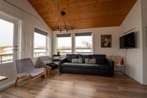 a living room with a black leather couch and windows at Smáratún Cottages & Chalets in Hellisholar