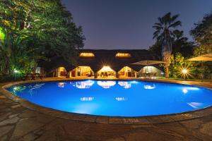 a large blue swimming pool in front of a building at Bayete Guest Lodge in Victoria Falls