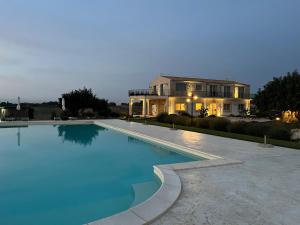a large swimming pool in front of a house at Carrua in Marzamemi